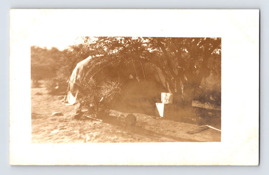 Real photo postcard of Native American wigwam style dwelling with brush covering and nearby tools 1910s AZO