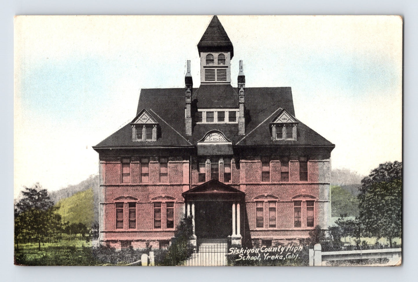 Yreka California Siskiyou County High School antique postcard showing a large brick academic building with central tower and hand-colored detail.