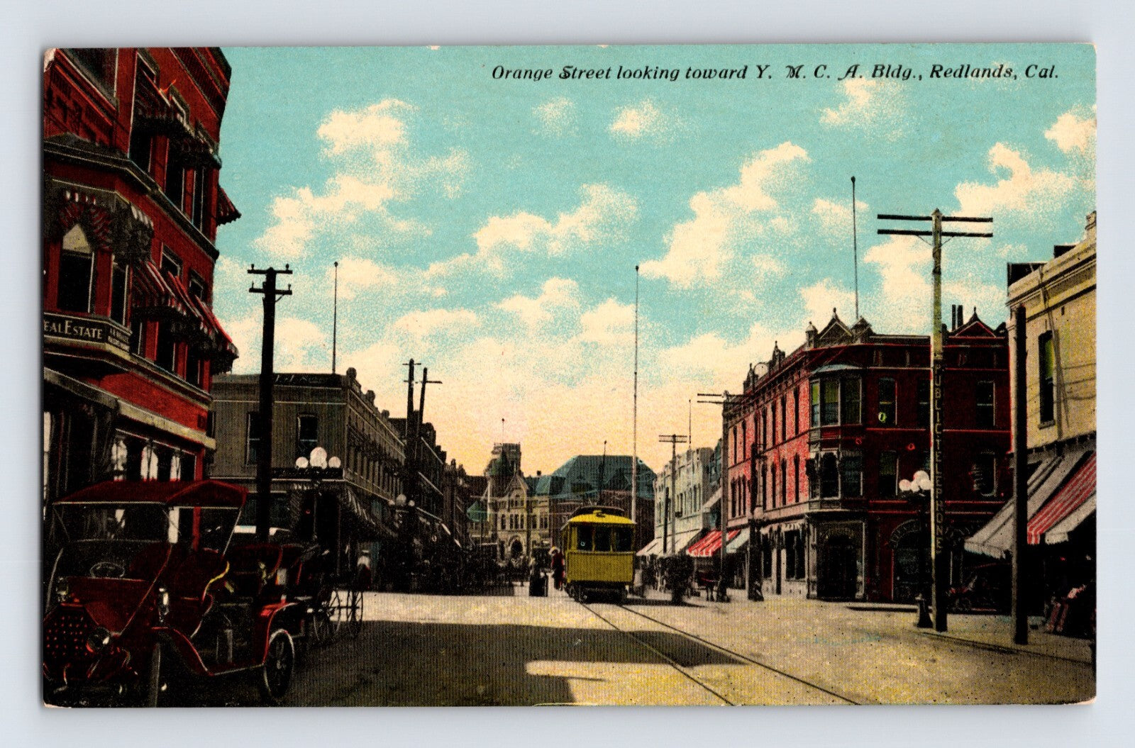 Colorized postcard view of Orange Street in downtown Redlands, California, featuring an electric streetcar, early automobiles, and commercial buildings along a busy business district.