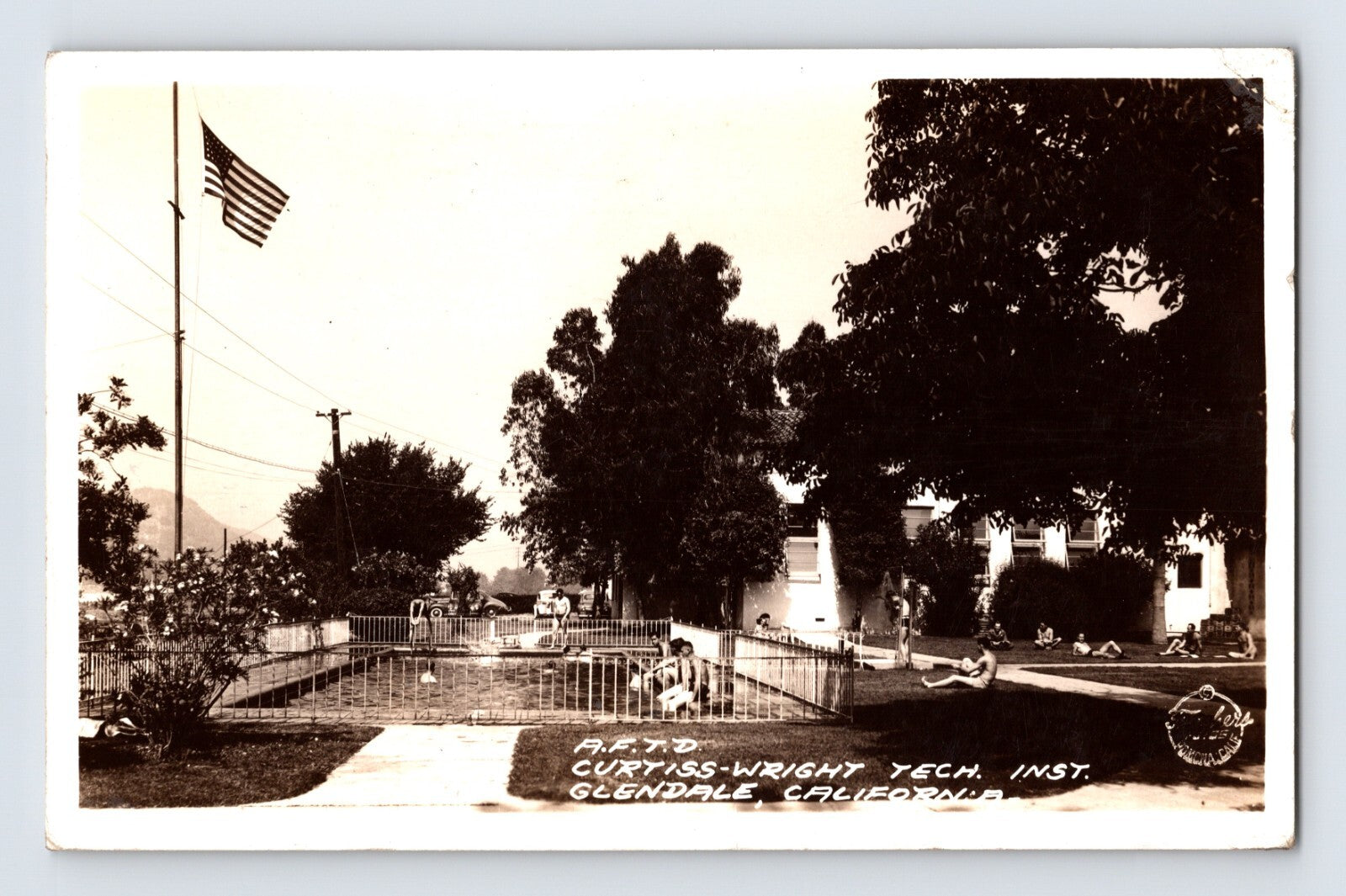 Curtiss Wright Technical Institute flight school campus with fenced pool area and American flag in Glendale, California, 1942 real photo postcard.