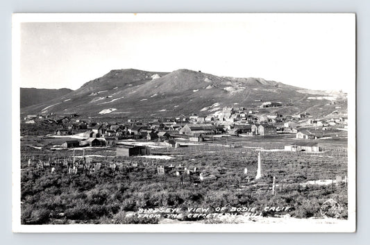 Black and white aerial view of Bodie California ghost town with cemetery in foreground and desert hills rising behind clustered wooden buildings