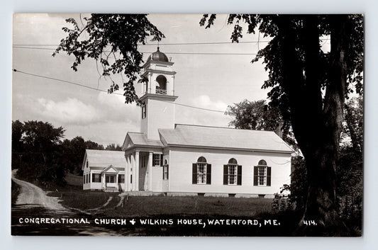 Black-and-white real photo postcard showing the Congregational Church and Wilkins House in Waterford, Maine, with a rural roadside setting and prominent church steeple.