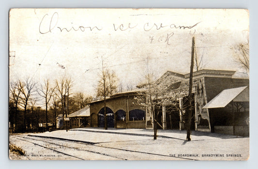 View of The Boardwalk at Brandywine Springs with arched pavilion building and bare trees in Wilmington, Delaware, 1905.