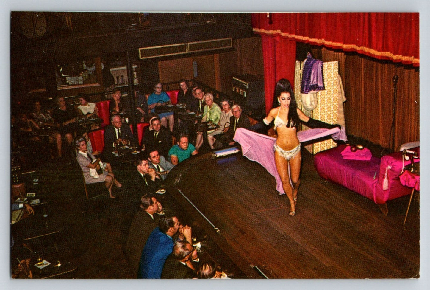 Color stage performance at Sho-Bar Club New Orleans showing burlesque dancer on small theater stage before seated audience, 1960s nightclub interior.