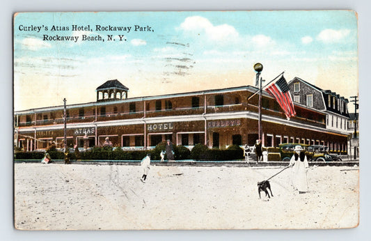 Color postcard view of Curley’s Atlas Hotel at Rockaway Beach, New York, showing the large beachfront hotel building with pedestrians, early automobiles, and an American flag.