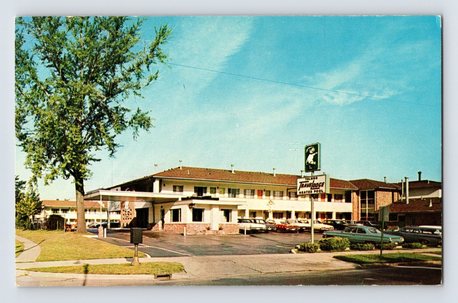 1970s Toledo Ohio Travelodge motel postcard showing roadside motor lodge with parking lot cars and roadside signage