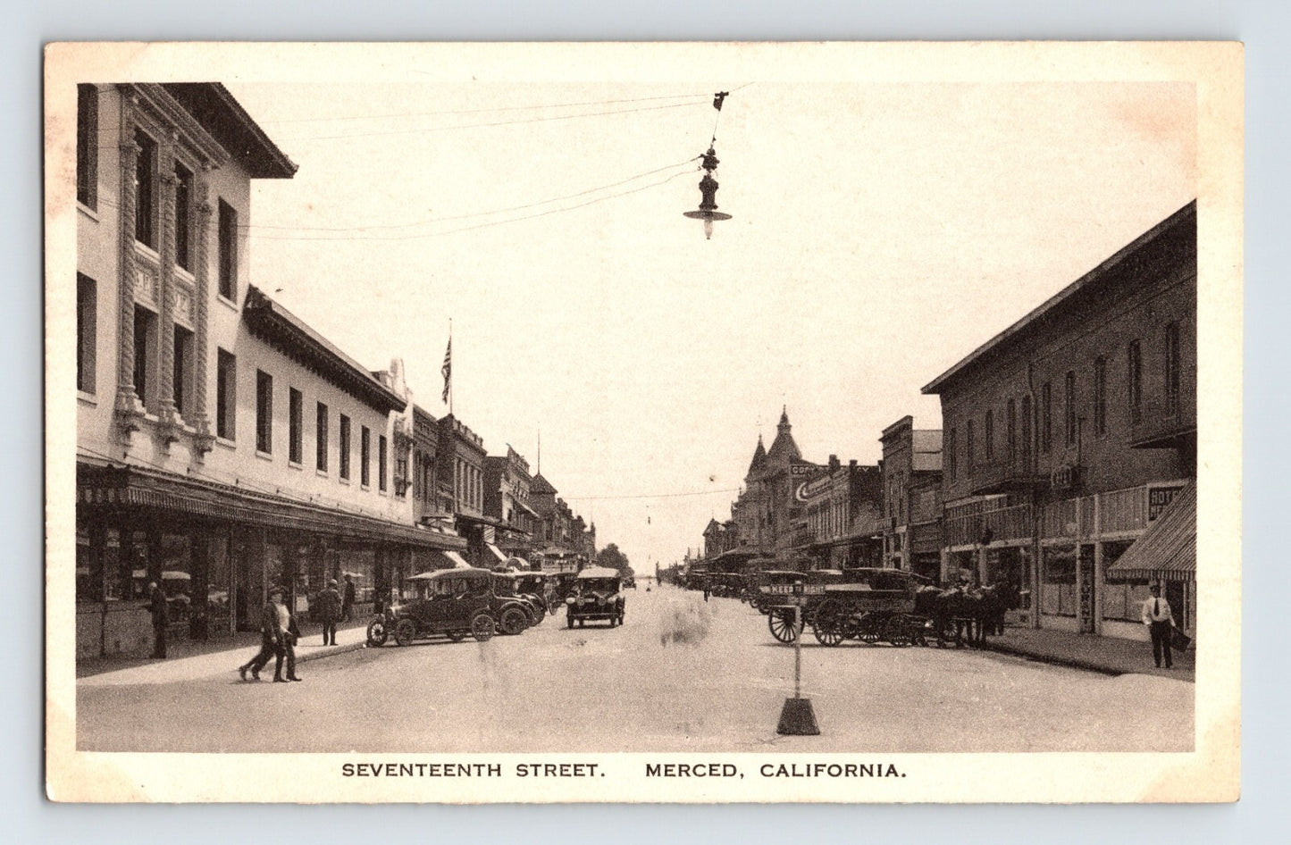 Vintage street scene of Seventeenth Street in Merced, California with buildings and cars.