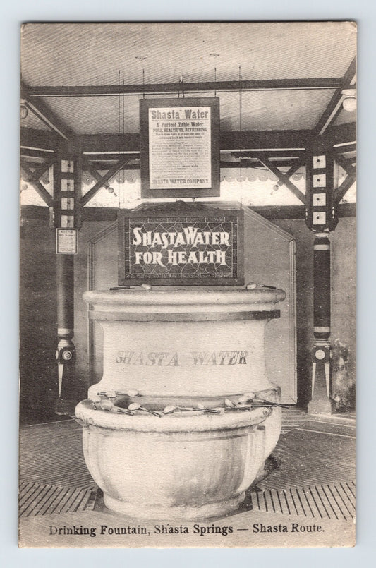 1910s postcard showing the Shasta Water drinking fountain at Shasta Springs, California, featuring an ornate mineral water display and advertising signage along the Shasta Route.