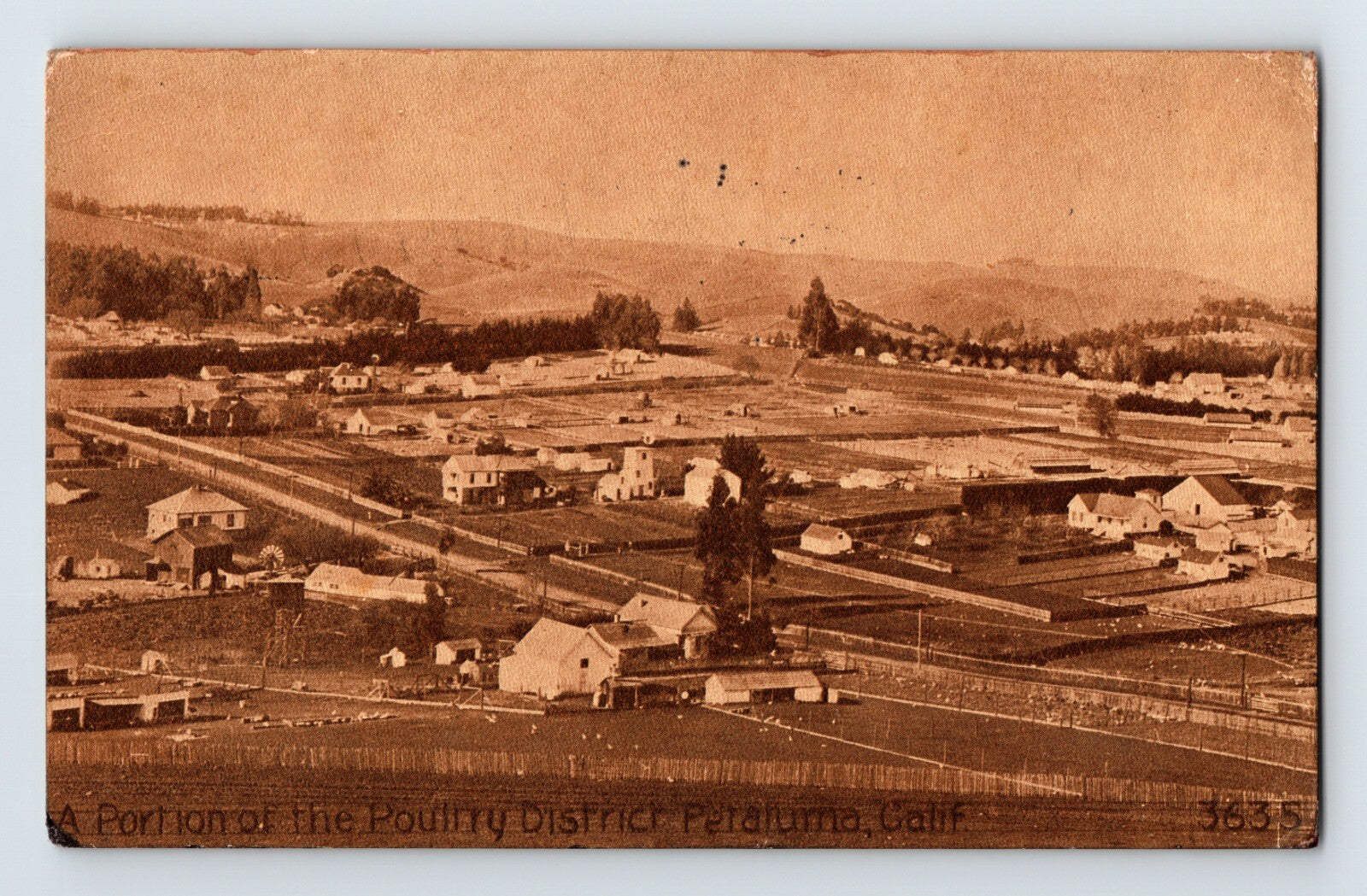 Vintage sepia-toned photograph of a small town with buildings and fields.