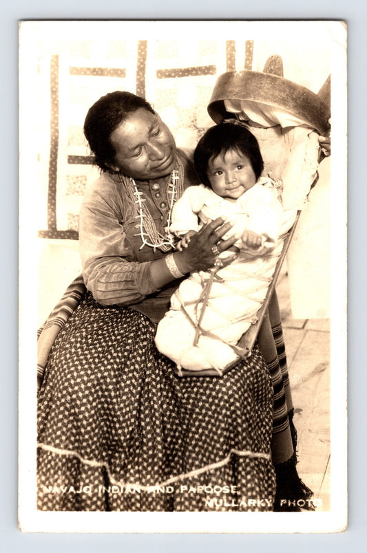 Postcard front showing a Navajo woman seated with a young child in a cradleboard, studio portrait credited Mullarky; postmarked 1939.