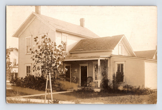 Vintage real photo postcard showing George Herthneck house with front porch and young tree in yard Holgate Ohio