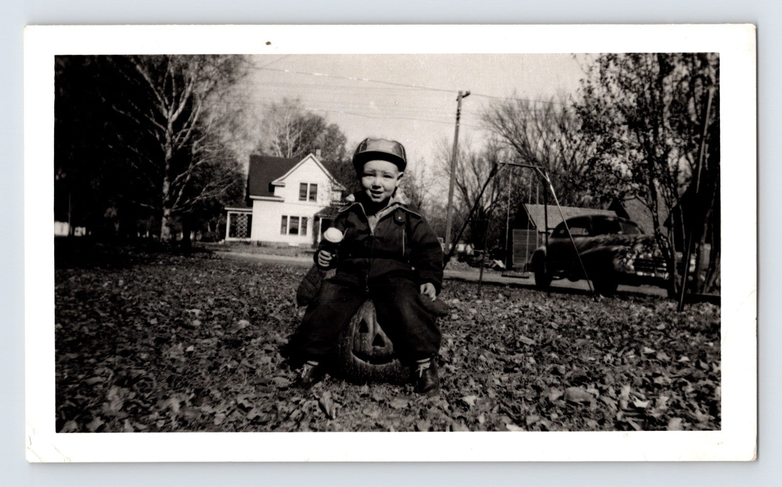 boy sitting on jack o lantern pumpkin yard autumn leaves 1949 Halloween photo