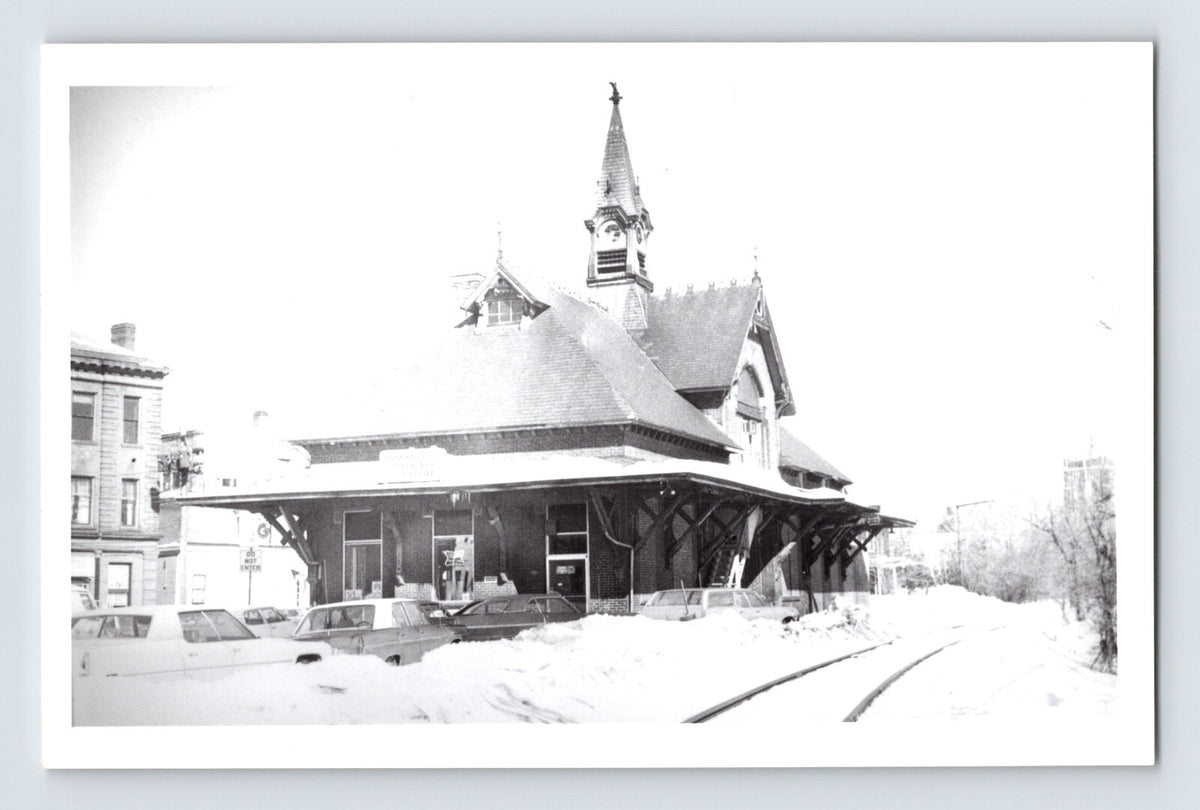 Real photo postcard of Leominster Massachusetts railroad train station depot in winter with snow covered ground and tracks