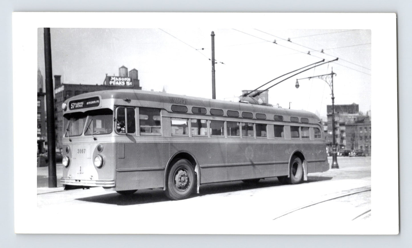 Chicago Surface Lines trolley bus 3067 on Route 57 Flushing Avenue Brown Place with overhead wires and Mason’s Peas sign in background black and white photo