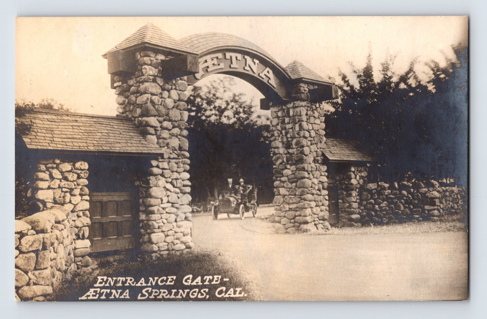 Aetna Springs California stone entrance gate real photo postcard with early automobile entering Napa County resort grounds.