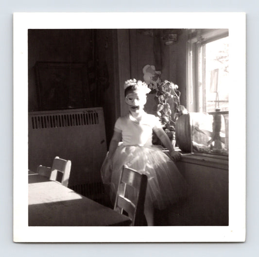 child in costume wearing mask and tulle skirt standing indoors by window Halloween snapshot photo