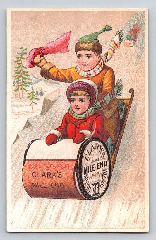 Victorian trade card advertising Clark’s Mile-End thread showing two children riding downhill on a spool-shaped sled through a snowy winter scene.