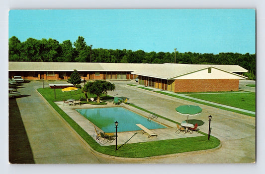 Aerial view of brick motel complex with central swimming pool, patio furniture, and manicured lawn in Yazoo City, Mississippi, 1960s