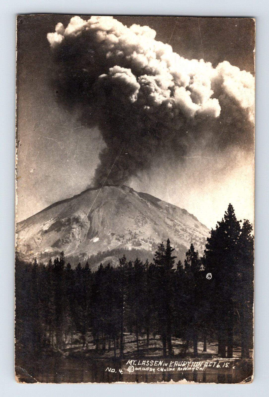 Real photo postcard of Mount Lassen eruption in California showing large volcanic ash plume rising above forested foreground, 191