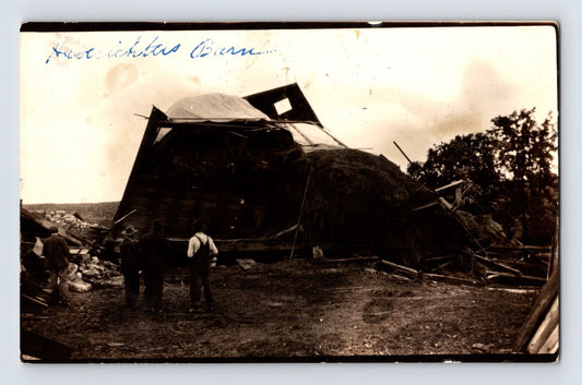 Real photo postcard showing collapsed Haberichter barn after 1924 tornado near Monona Iowa with men standing beside wreckage
