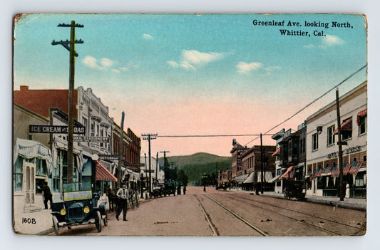Greenleaf Avenue Whittier California storefronts with ice cream parlor sign, early automobile and streetcar tracks, 1910s color postcard
