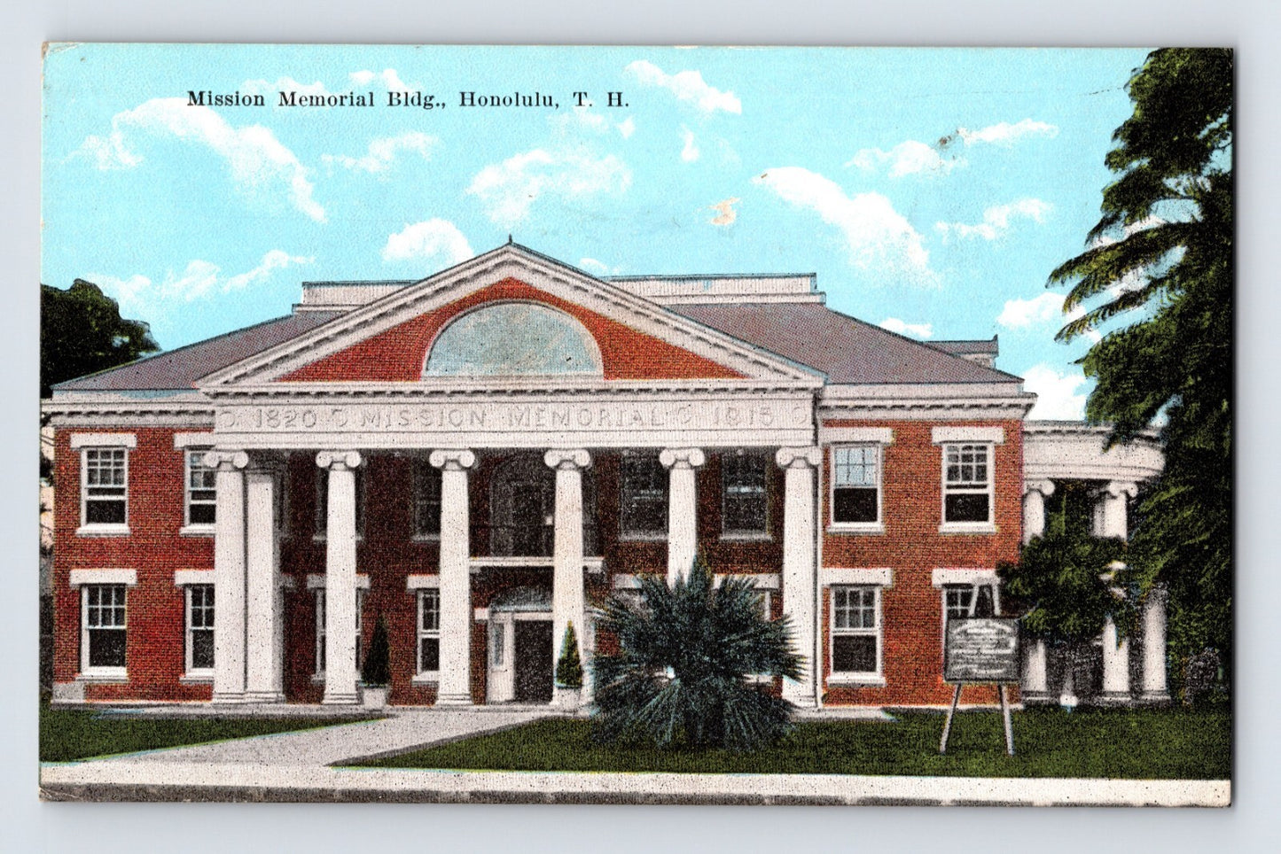 Color postcard view of the Mission Memorial Building in Honolulu, Hawaii, showing the red-brick neoclassical structure with white columns and tropical landscaping.