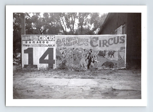 1955 Kelly Miller Bros Circus billboard banner with large July 14 date panel and illustrated elephants, camels, and giraffe mounted beside a wooden building.