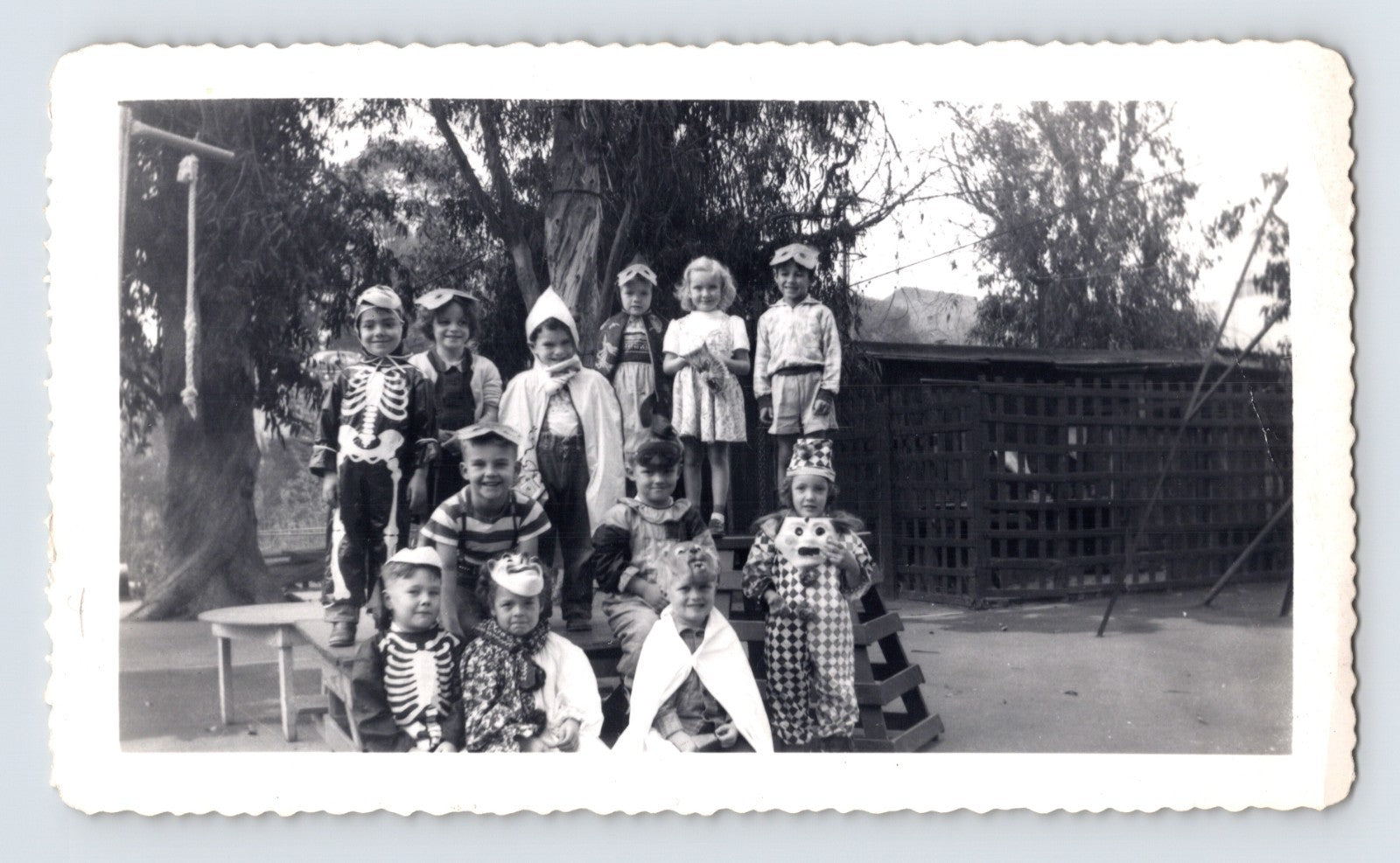 Halloween children group costumes skeleton clown masks schoolyard 1950s photo