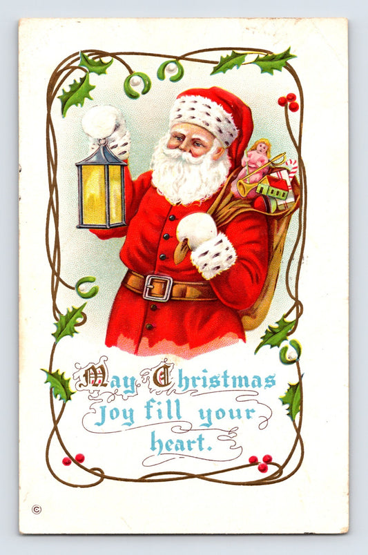 Embossed Christmas postcard featuring Santa Claus holding snowballs and a lantern with a sack of toys framed by holly decorations.