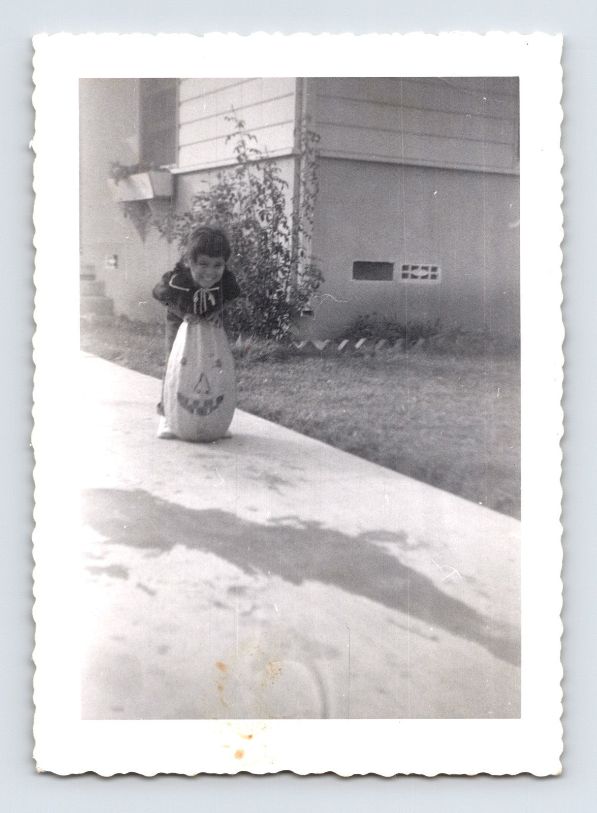 Child with Halloween pumpkin trick or treat bag sidewalk 1950s photo