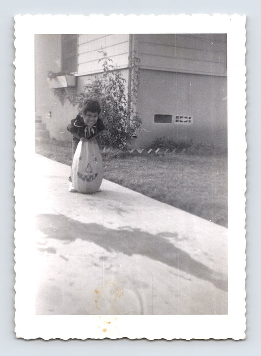 Child with Halloween pumpkin trick or treat bag sidewalk 1950s photo