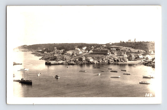 Monhegan Maine village harbor with boats, pier and clustered shoreline buildings in elevated 1956 real photo view