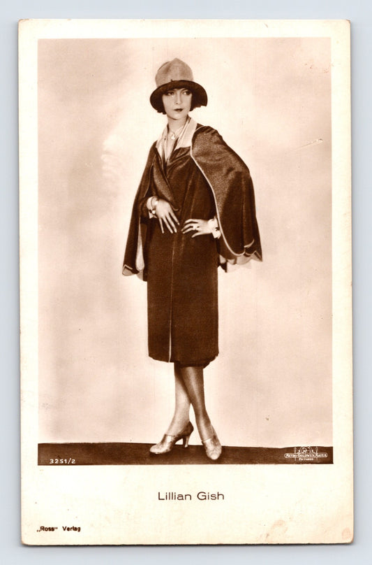 Sepia-tone full-length portrait postcard of silent film actress Lillian Gish wearing a cloche hat and fashionable dark dress in a studio publicity photograph.