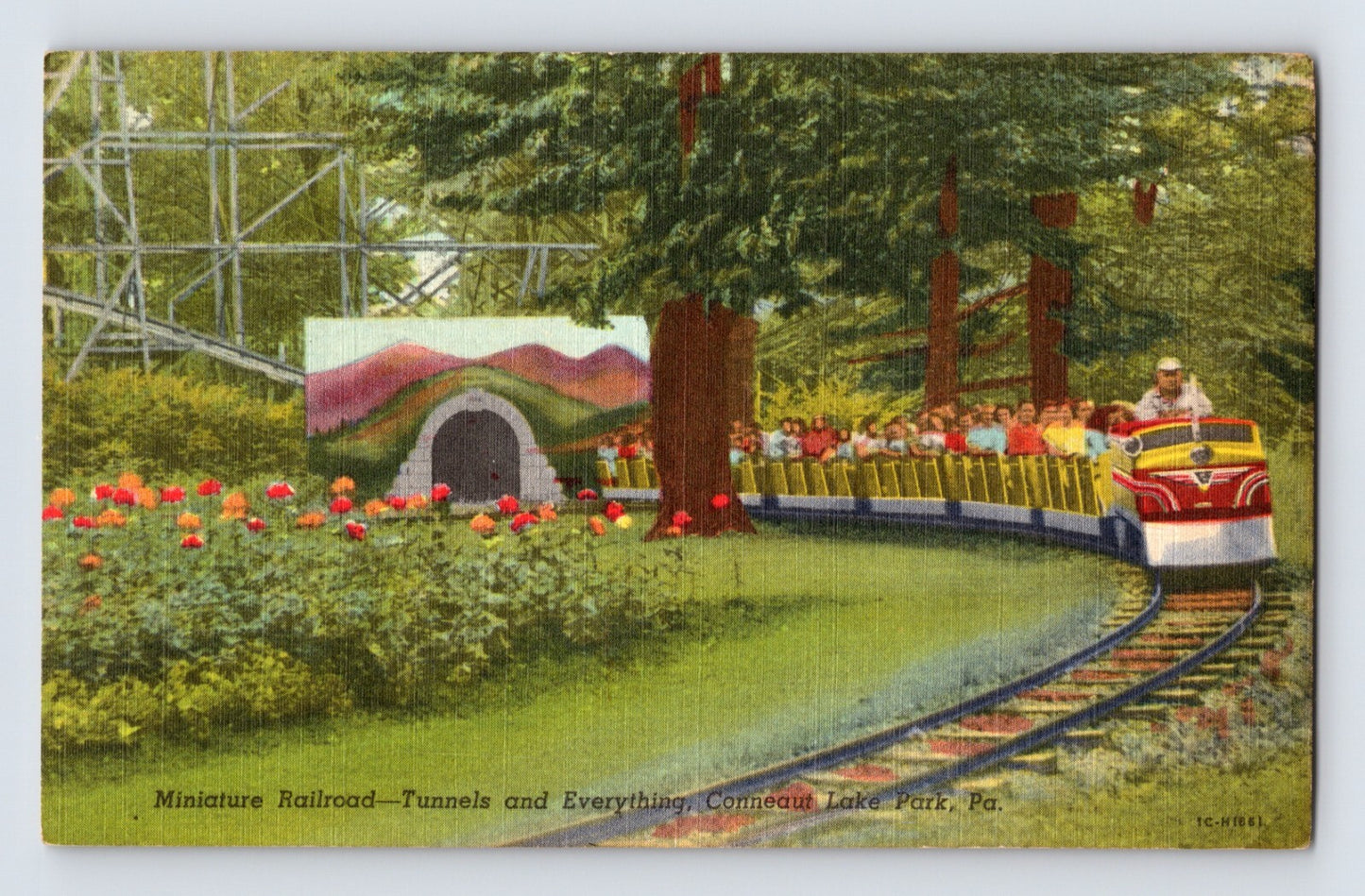 Conneaut Lake Park miniature railroad train rounding a curved track beside flowerbeds and trees, passengers seated in open cars near tunnel entrance, 1940s linen postcard Pennsylvania amusement park scene