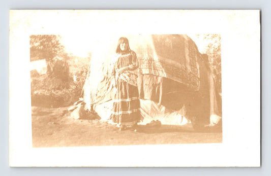 Vintage sepia-toned photograph of a person in a long dress sitting outdoors.