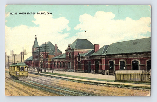 1910s postcard showing Union Station in Toledo, Ohio, with railroad depot buildings, street railway tracks, and an electric trolley approaching the station frontage.