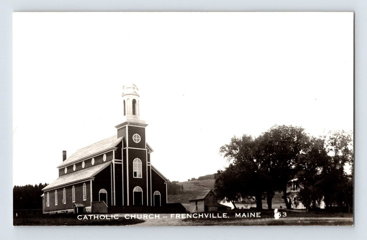 Catholic Church building with steeple and adjacent trees in Frenchville, Maine, 1950s real photo postcard.