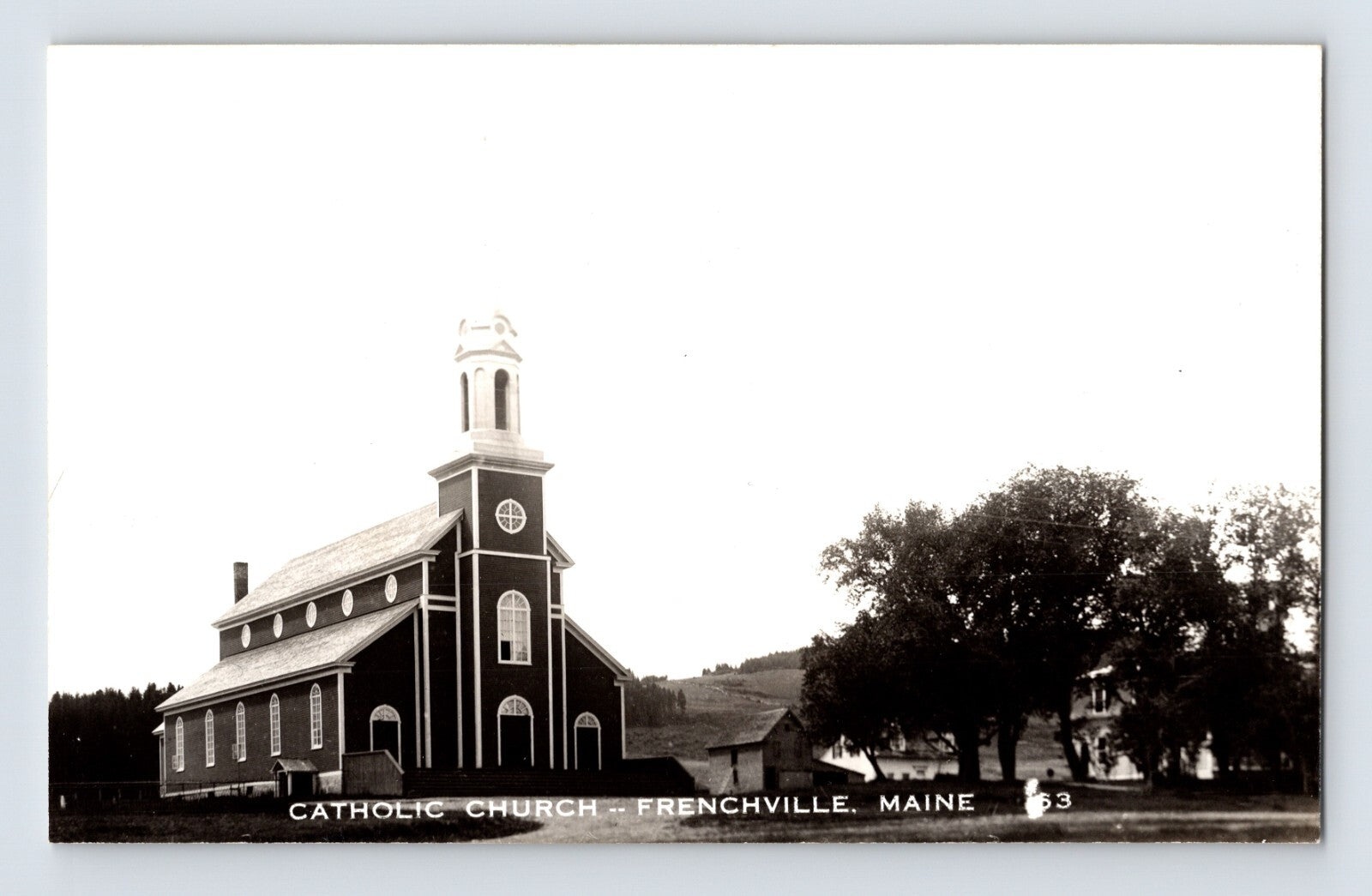 Catholic Church building with steeple and adjacent trees in Frenchville, Maine, 1950s real photo postcard.