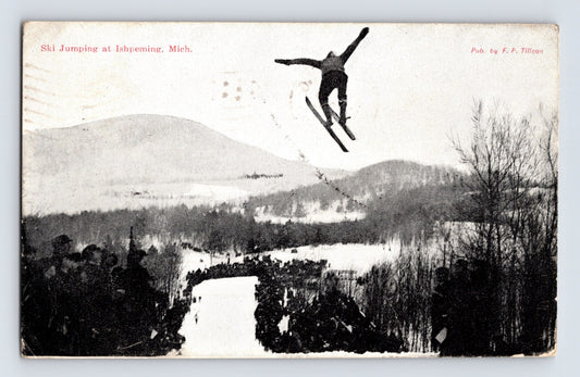 Ishpeming Michigan postcard showing ski jumper airborne above snowy hillside and crowd 1910 winter scene