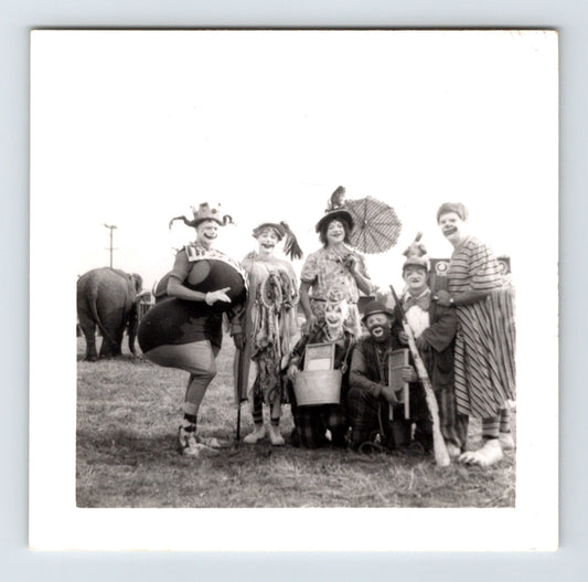 1954 black and white photograph of Clyde Beatty Circus clowns posing together in costume with elephant in background, Concordia Kansas.