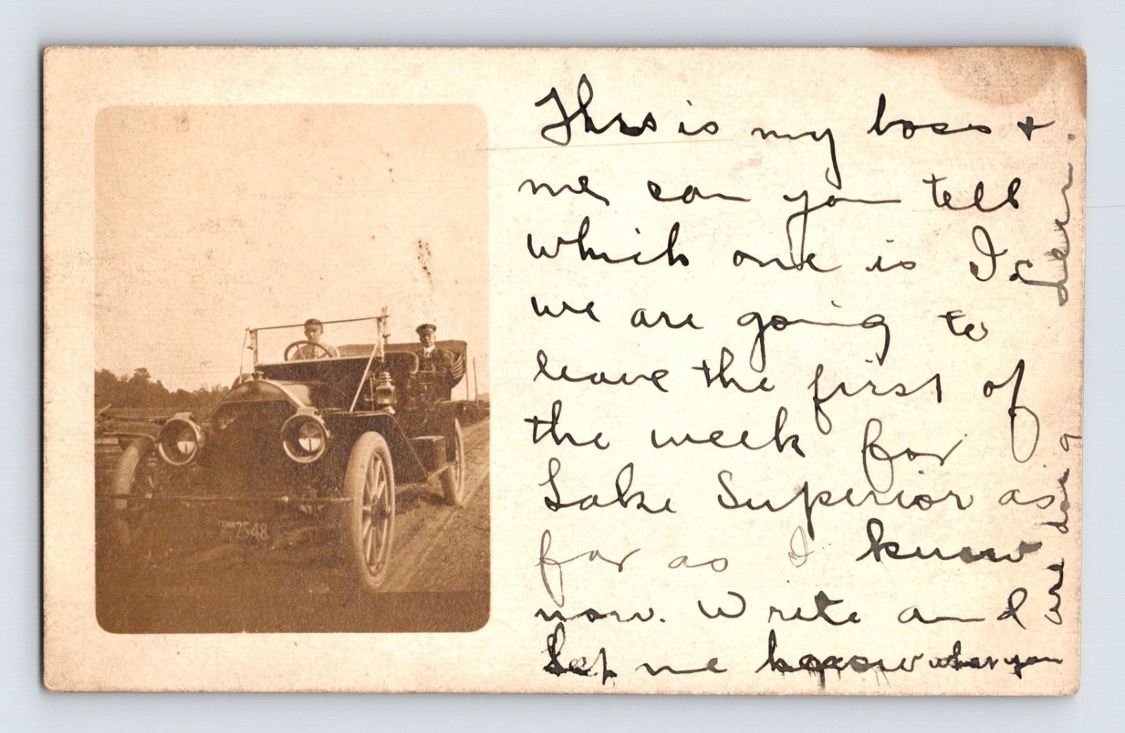 Real photo postcard of early open touring automobile with two men seated inside on dirt road near Indianapolis Indiana