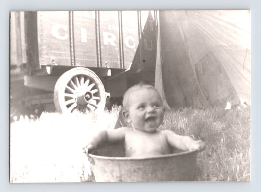 Barnes Sells Floto Circus baby bathing in metal wash tub beside circus wagon and tent 1940s circus lot photograph
