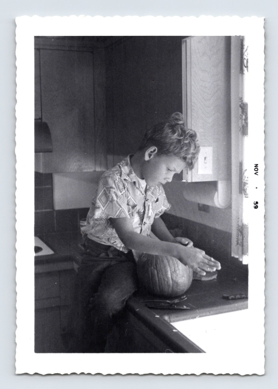 Boy carving pumpkin kitchen countertop mid century Halloween snapshot