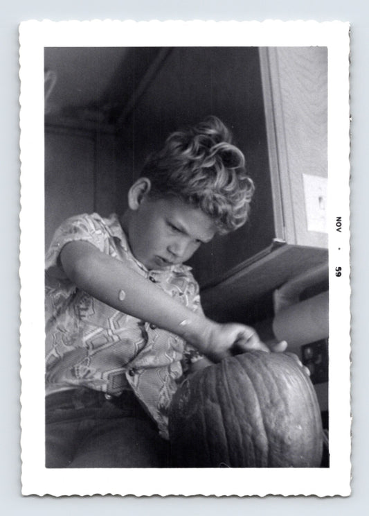 Boy carving pumpkin kitchen counter Halloween preparation mid century snapshot