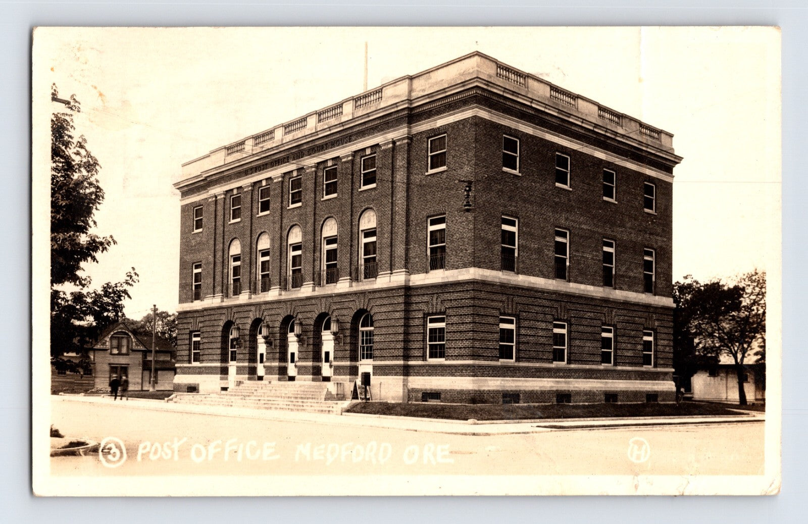 Medford Oregon Post Office 1925 real photo postcard showing large brick federal building on corner street with arched windows and pedestrians