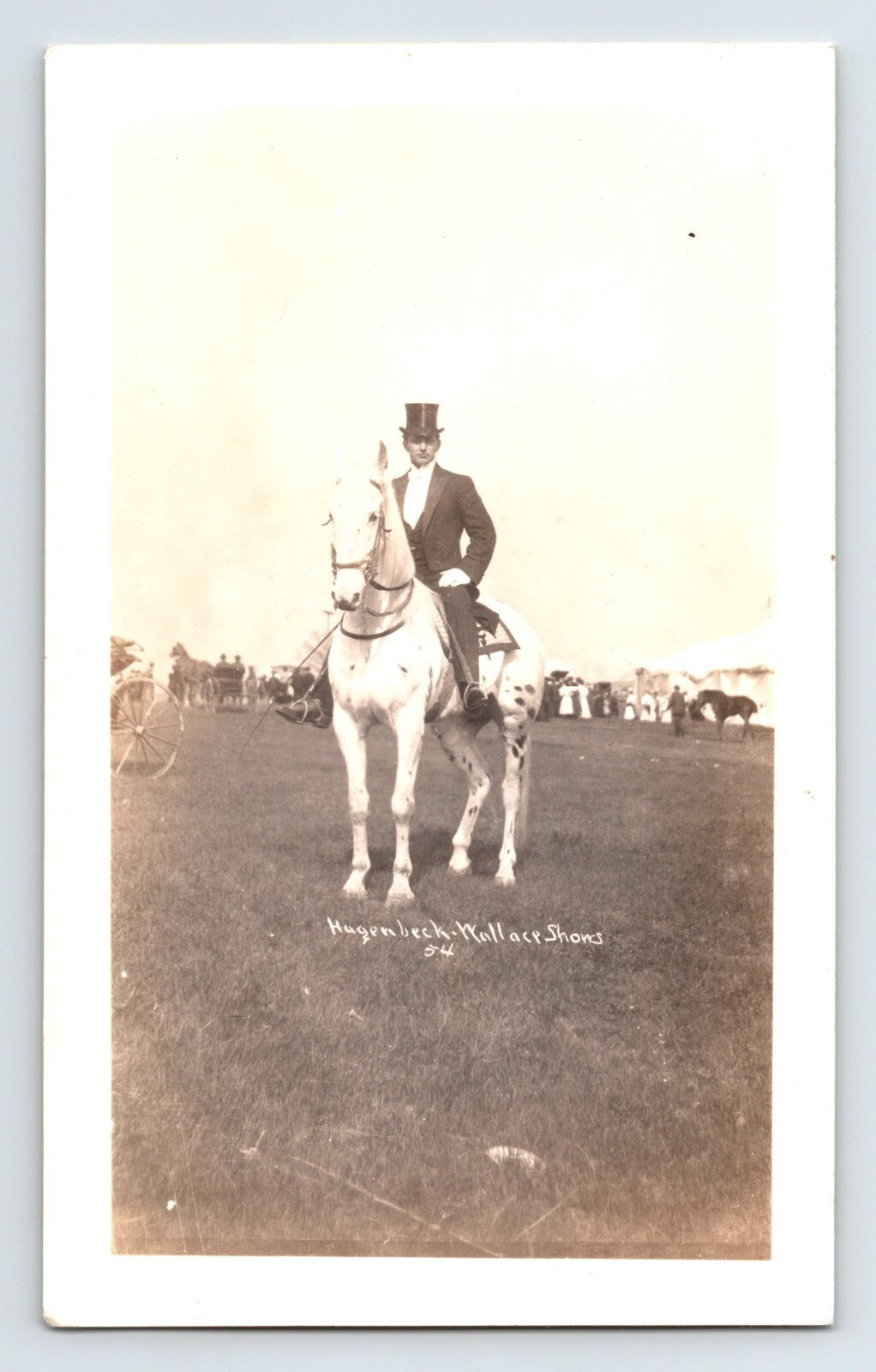 Hagenbeck Wallace Shows circus performer on white horse formal attire top hat equestrian field setting with crowd in background vintage photograph