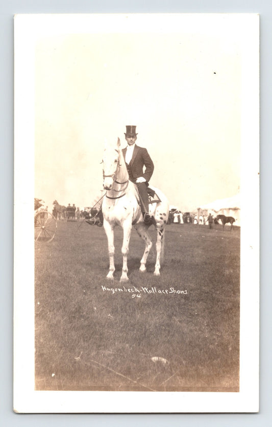 Hagenbeck Wallace Shows circus performer on white horse formal attire top hat equestrian field setting with crowd in background vintage photograph
