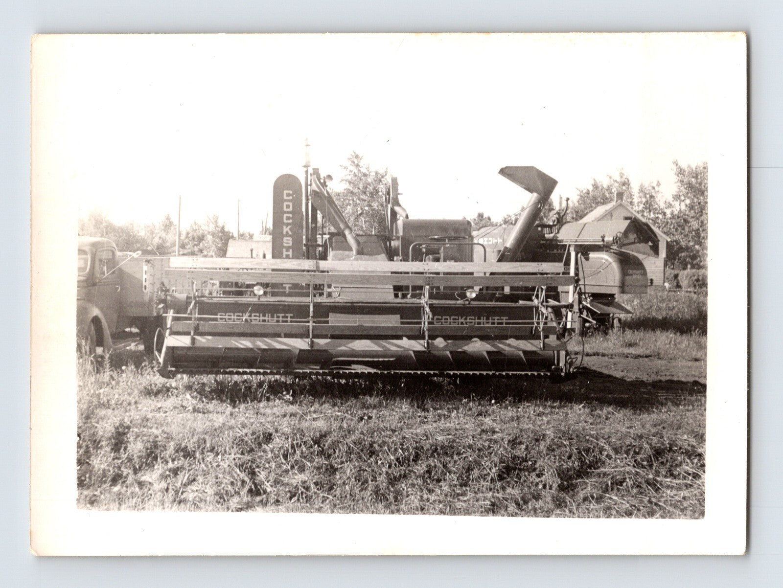 Vintage black and white photograph of a combine harvester in a field.