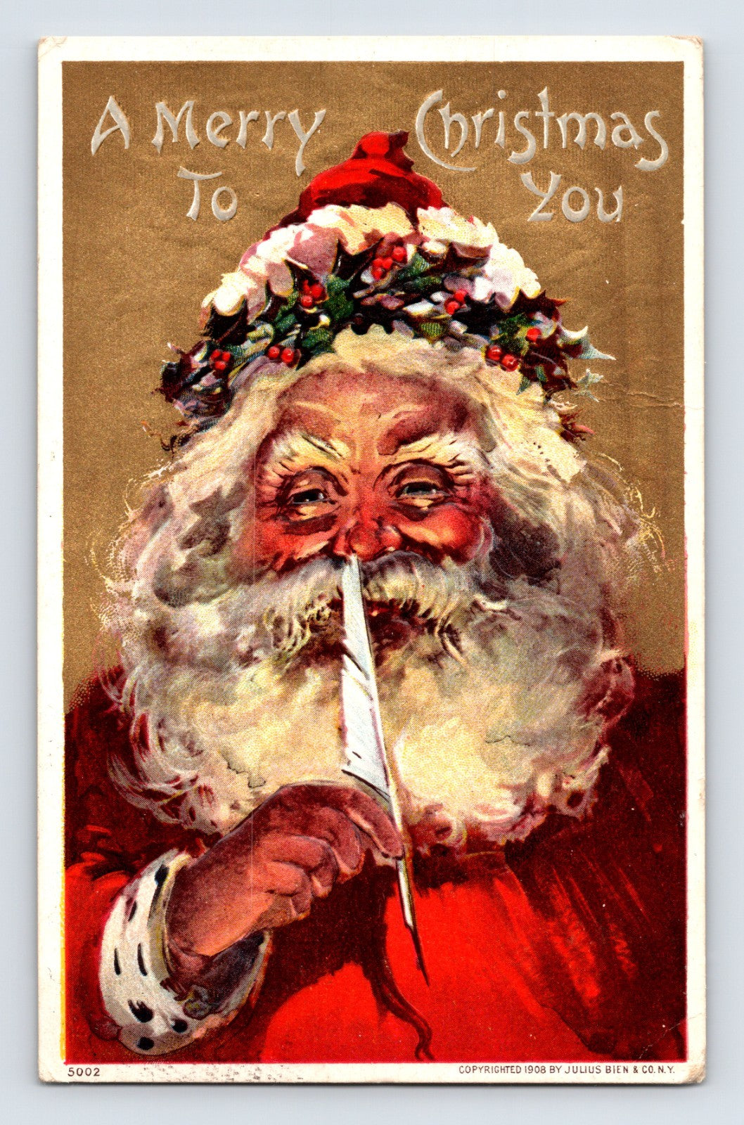 Close-up Santa Claus portrait holding a white feather quill beneath holly leaves and a red cap on this 1908 Julius Bien Christmas postcard.