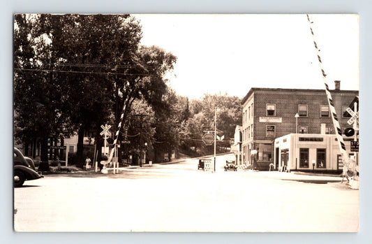Real photo postcard of Randolph Vermont Main Street with Shell gas station and railroad crossing gates